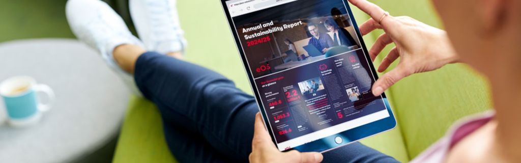 Човек на зелен диван, разглеждащ Годишния и Отчета за устойчивост на EOS 2024/25 на таблет